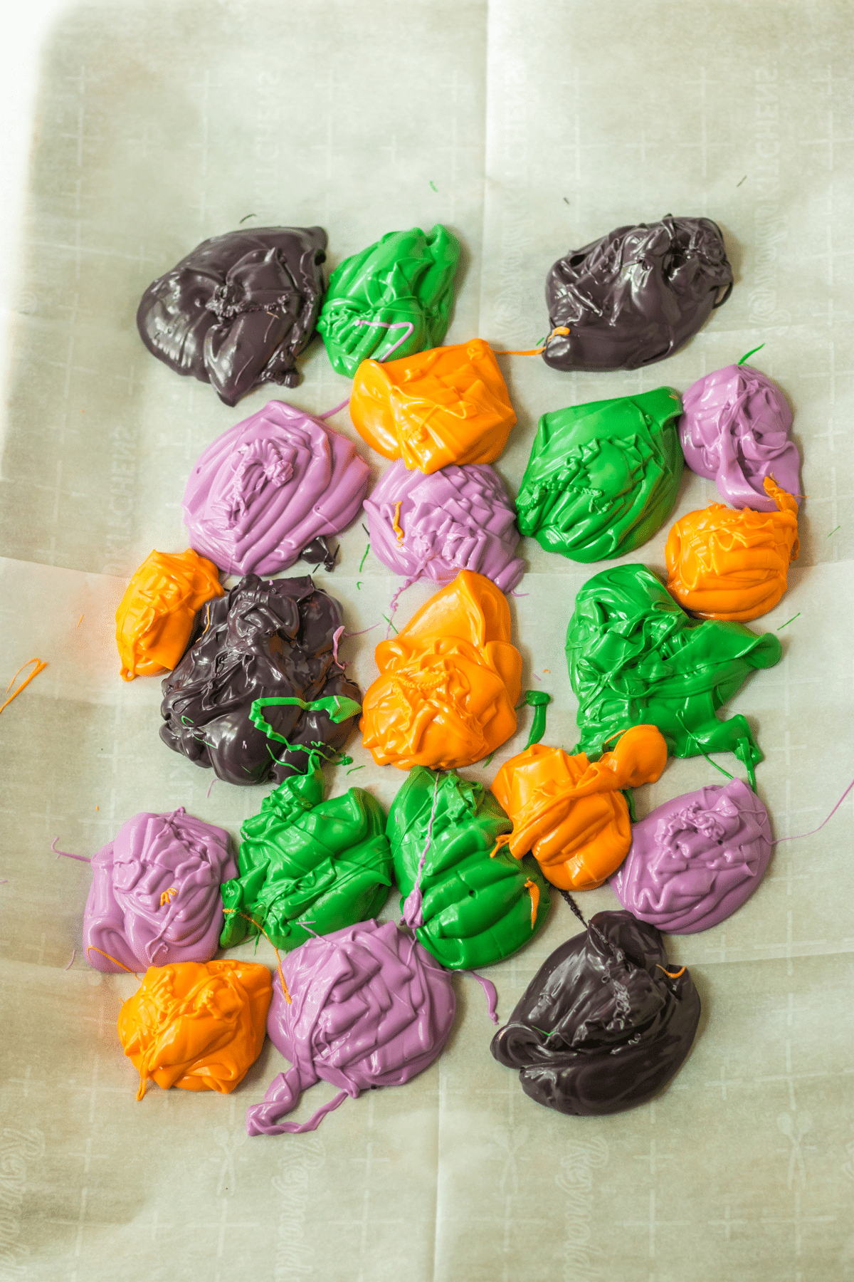 Next step in making Halloween Cookie Bark is to put dollops of the colors all over the lined sheet pan and swirl them together.