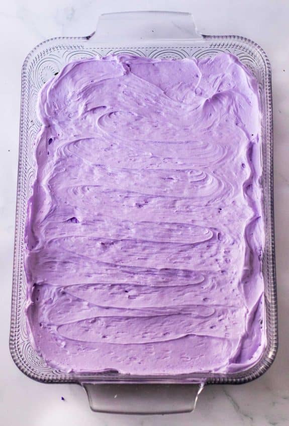 A purple icing cake in a glass pan.