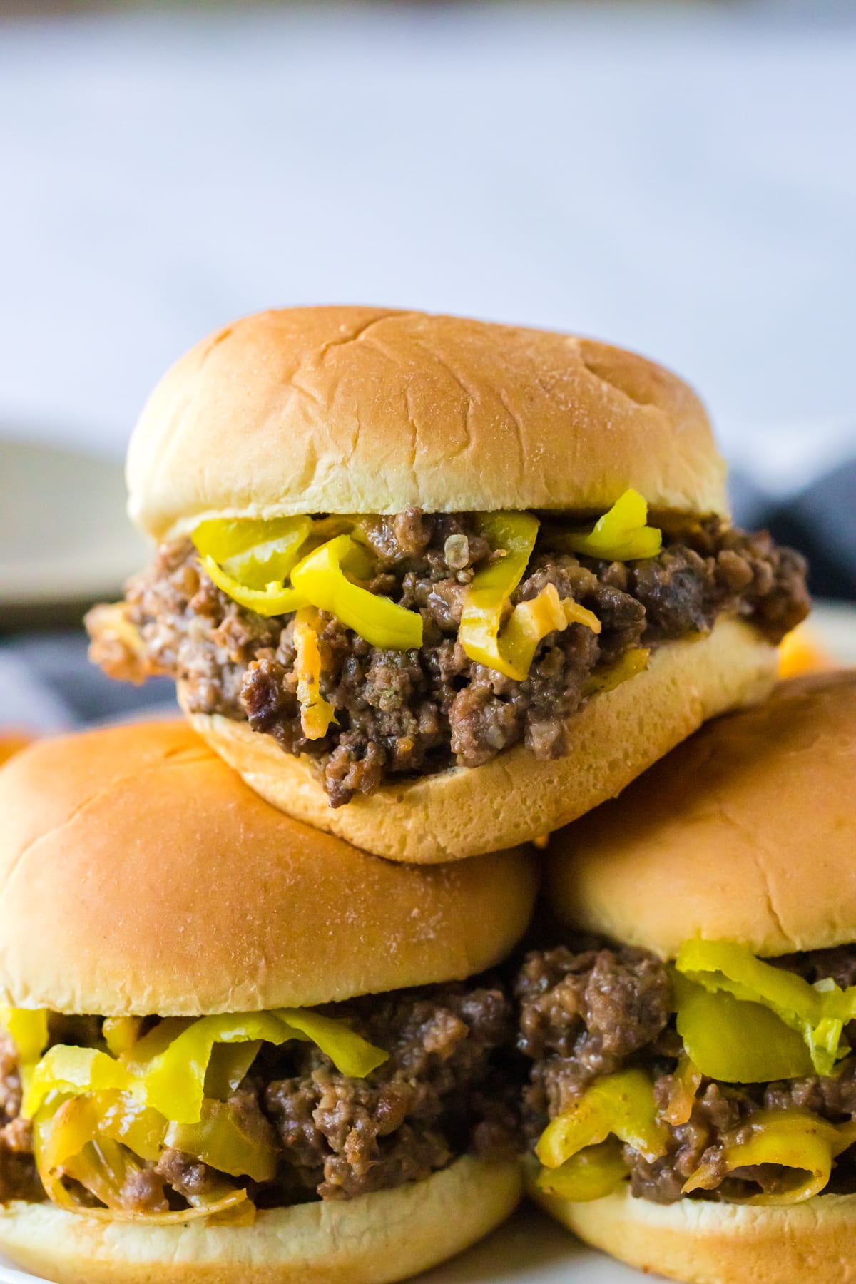 A stack of Slow Cooker Mississippi Sloppy Joes with peppers and onions on a plate.