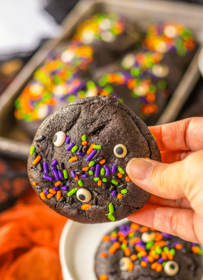 A hand holding a halloween cookie with sprinkles on it.