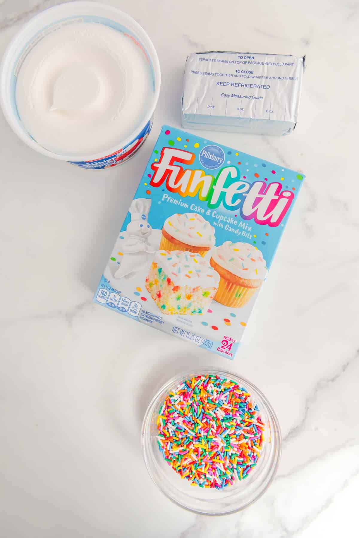 The ingredients for a funfetti cake are shown on a marble table.