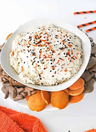 A bowl of halloween dip topped with cookies and crackers.