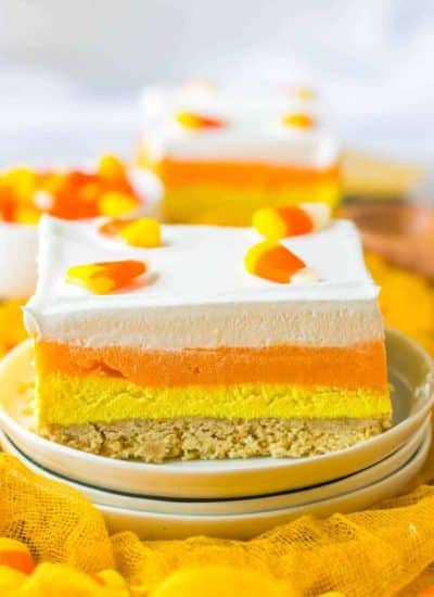 A slice of candy corn cheesecake on a plate.