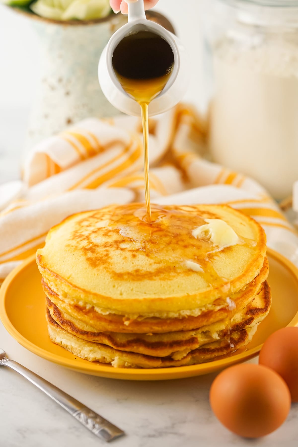 A stack of Freshly cooked Homemade Pancakes being poured with syrup.