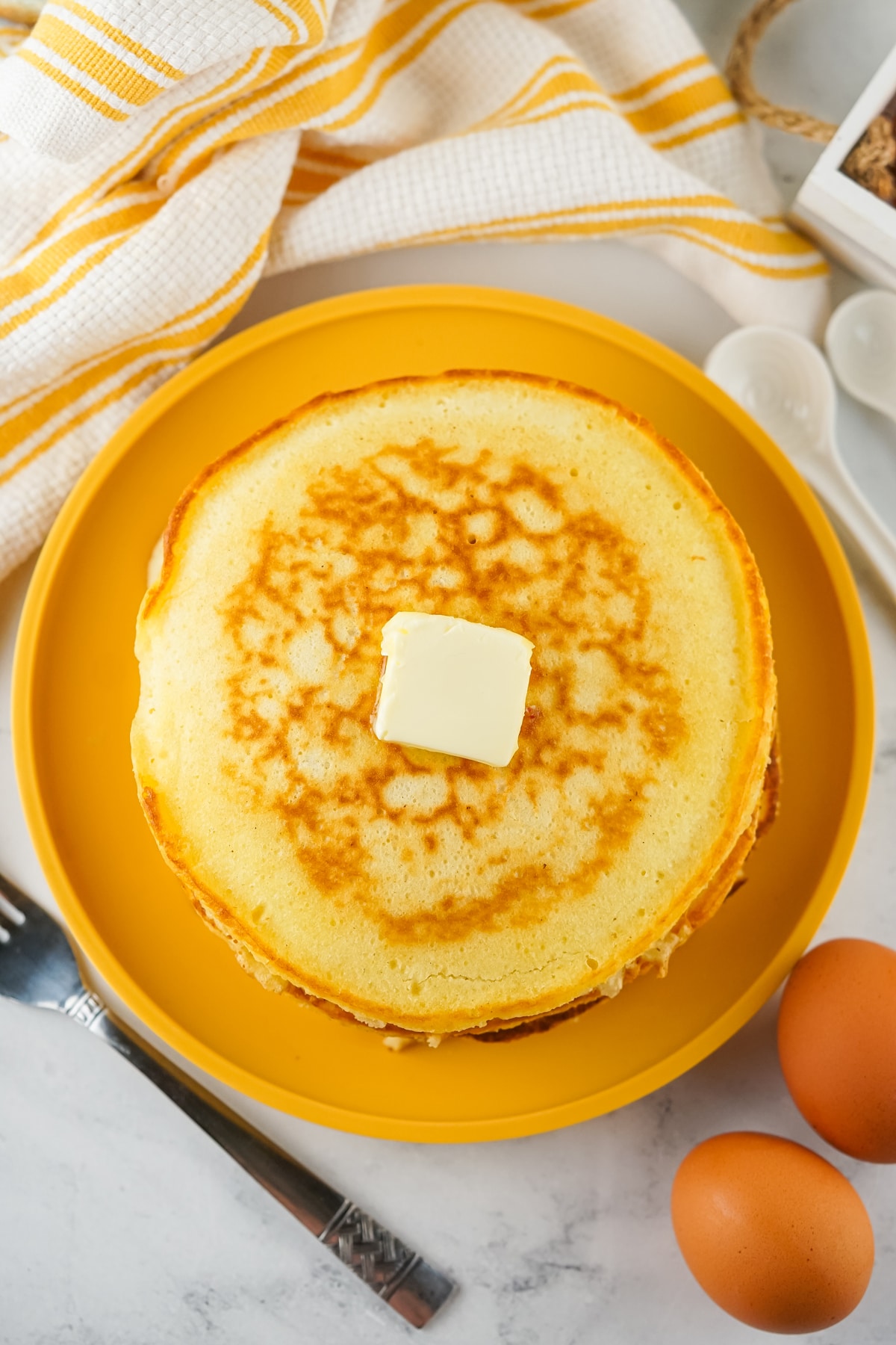 Cooked pancakes using Homemade Pancake Mix on a yellow plate with butter and eggs.