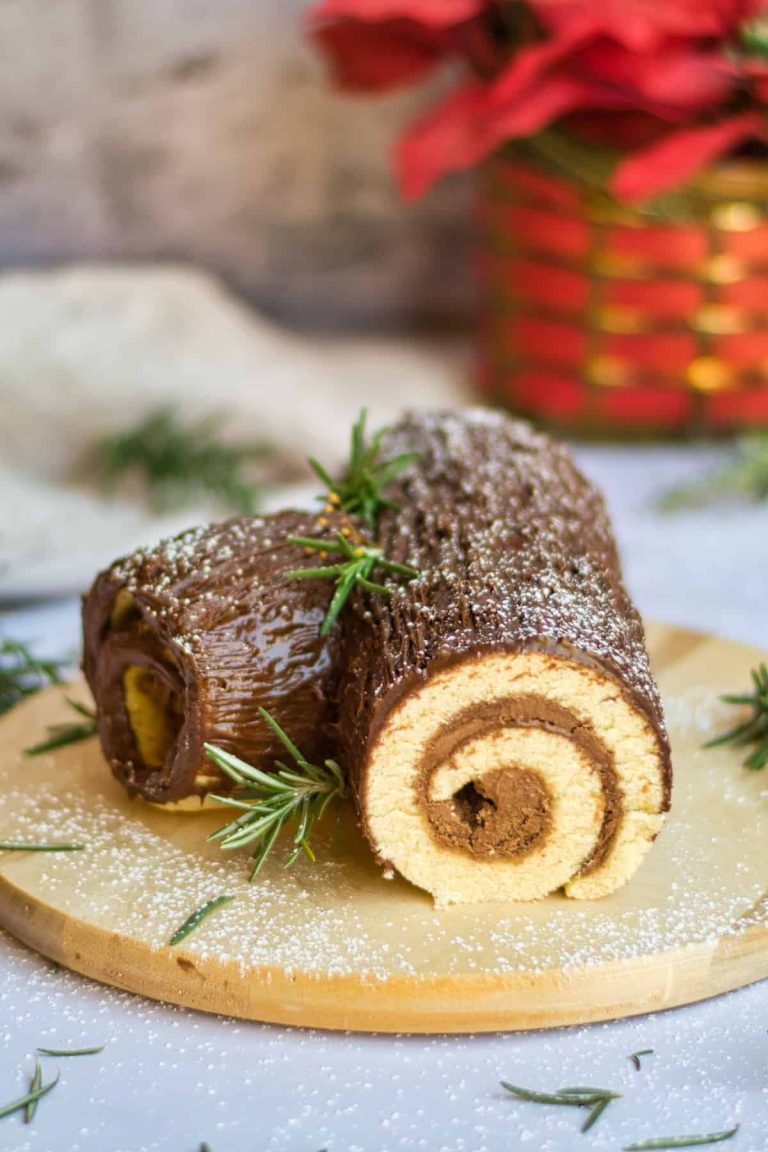 A chocolate christmas roll on a wooden cutting board.