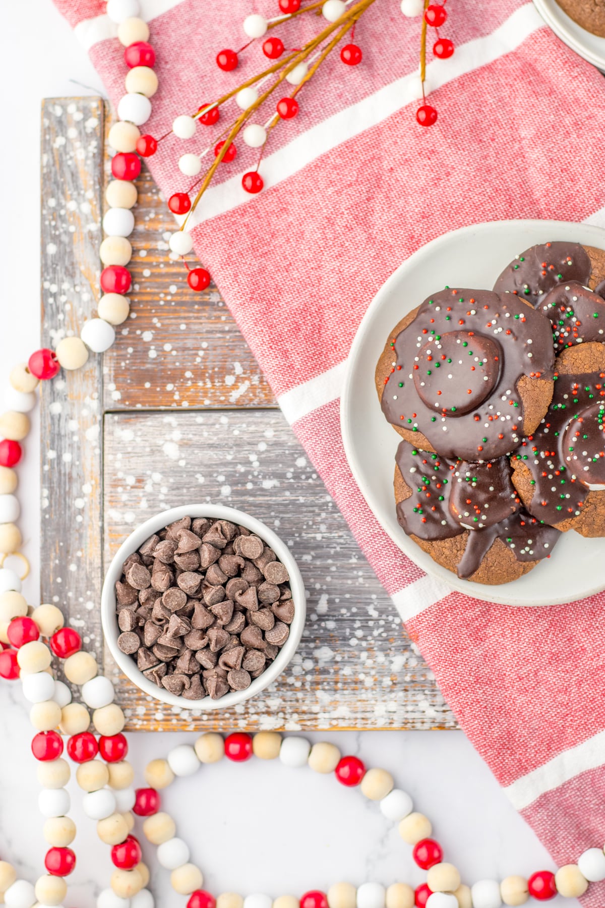 Hot Chocolate Cookies on a table with red and white decorations and a cup of chocolate chips.