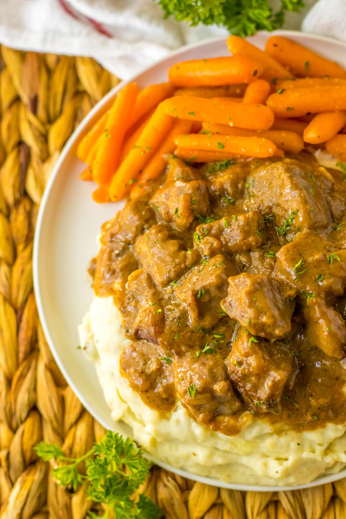 A closer look on a plate of Beef Tips with carrots and mashed potatoes.