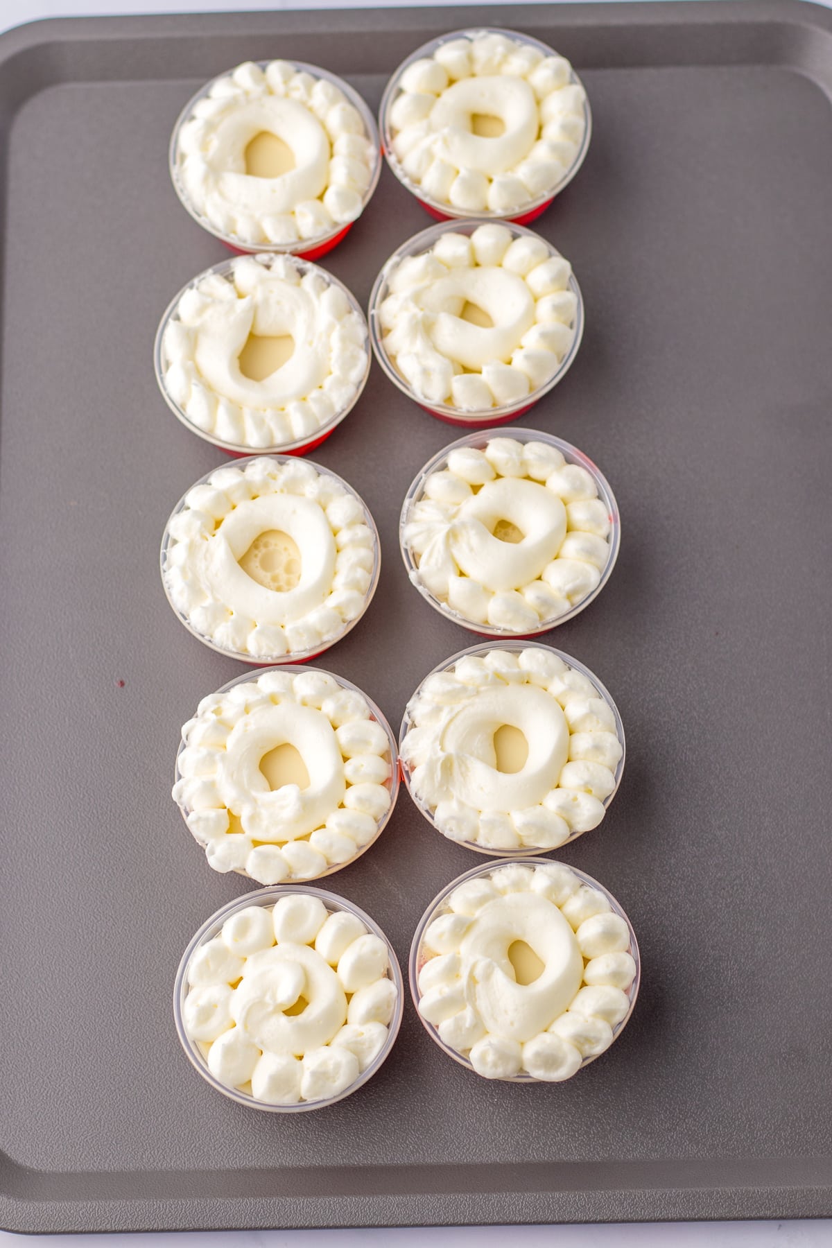 A tray of Santa Hat Jello Shots with whipped cream on top