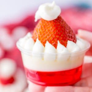 A person holding Santa Hat Jello Shot with strawberry on top