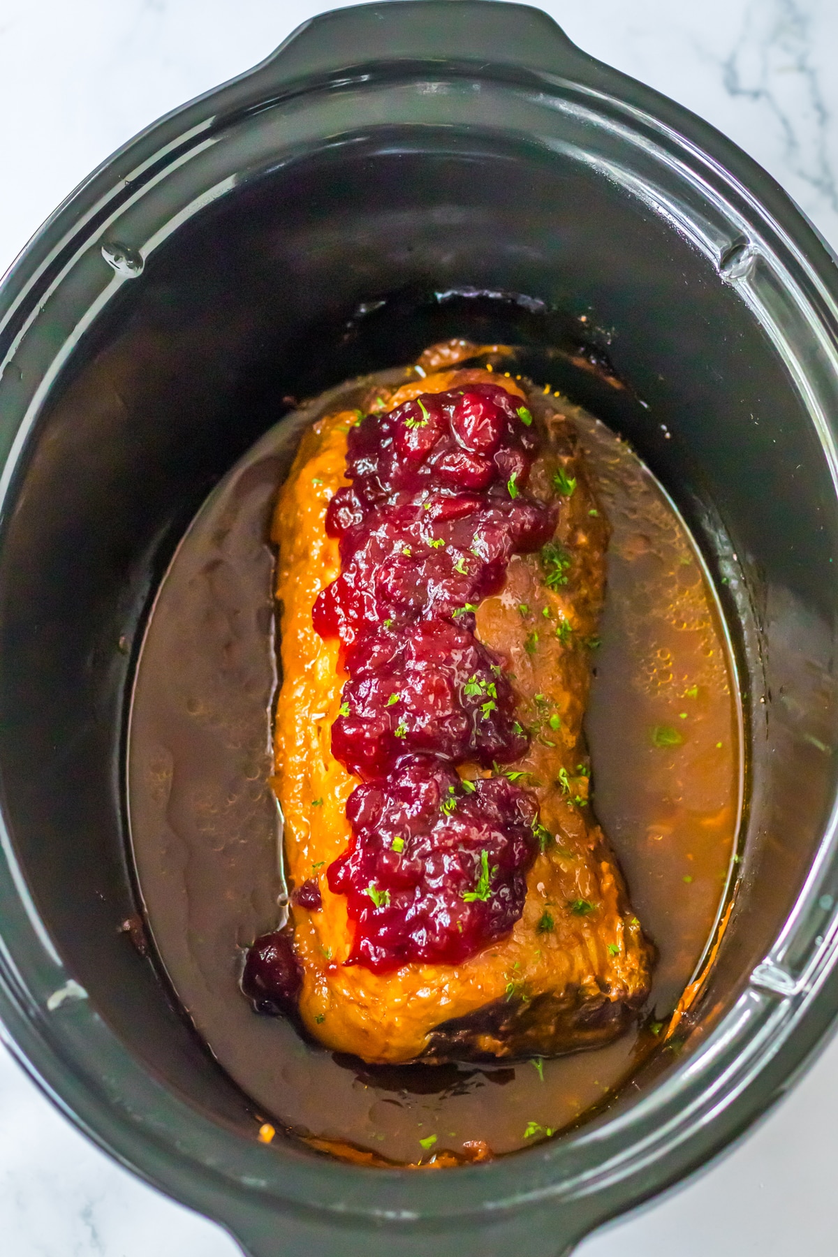 A crock pot filled with meat and cranberry sauce.