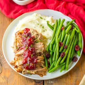 Pork tenderloin with cranberry sauce and green beans on a plate.