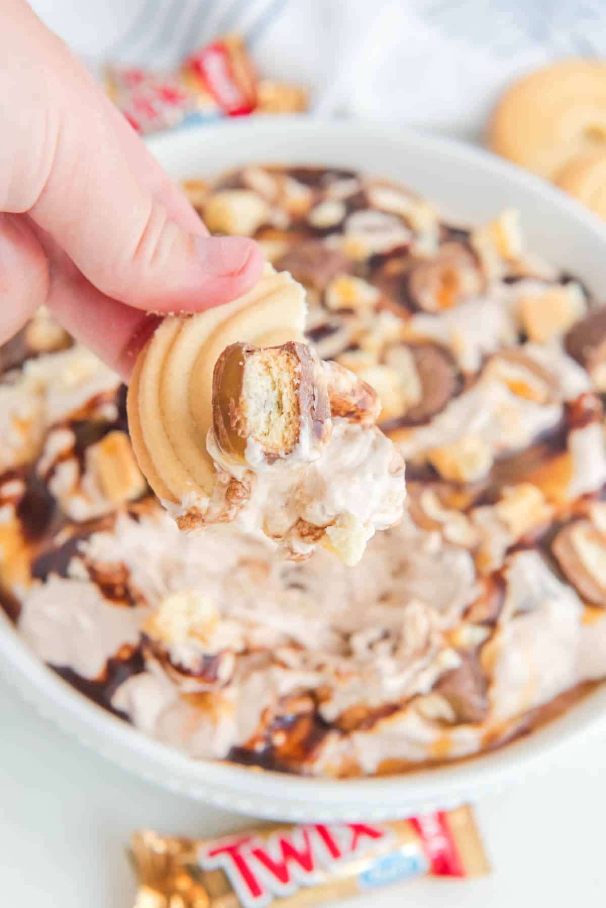A person is dipping a cookie into a bowl of ice cream.