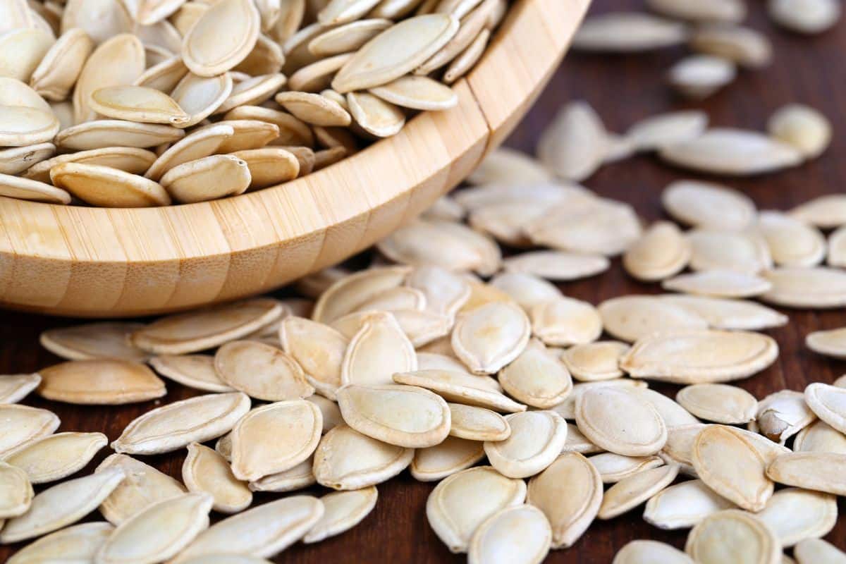 A guide on saving pumpkin seeds for consumption, displayed in a wooden bowl.