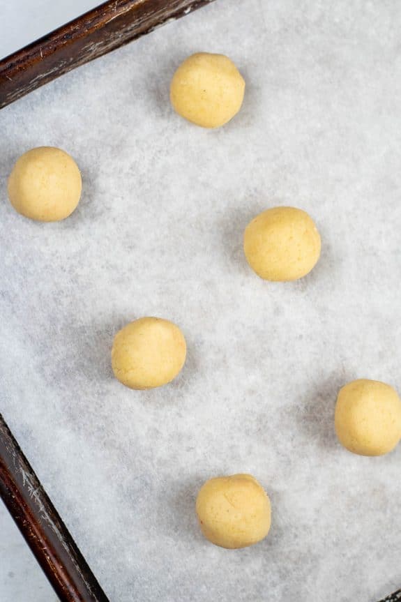 A baking sheet with a tray of round cookie dough on it.