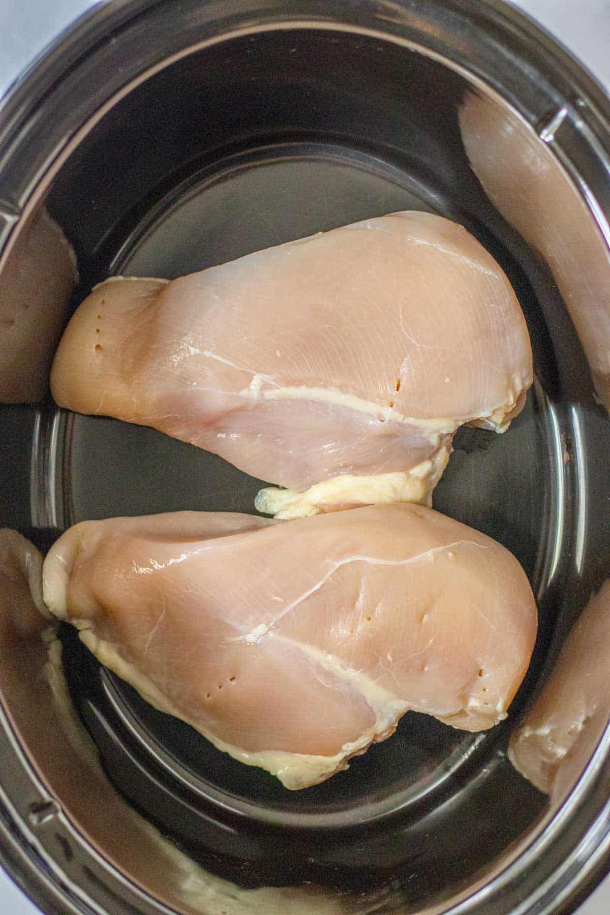 Two chicken breasts in a slow cooker.