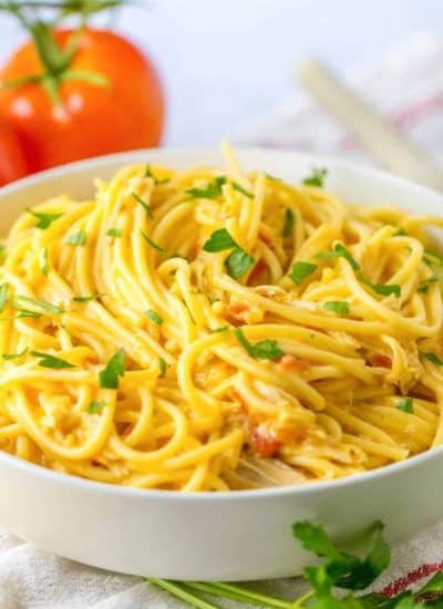 A bowl of spaghetti with tomatoes and herbs.