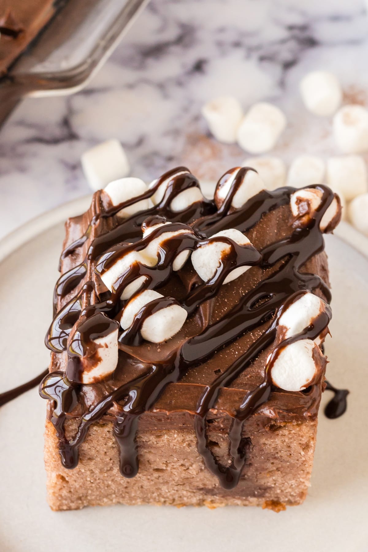 A piece of Hot Chocolate Poke Cake with marshmallows on top.