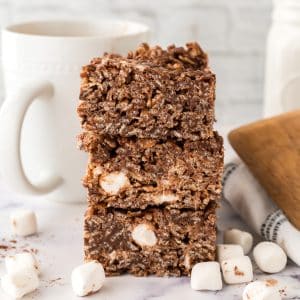 A stack of chocolate granola bars with marshmallows and a cup of coffee.