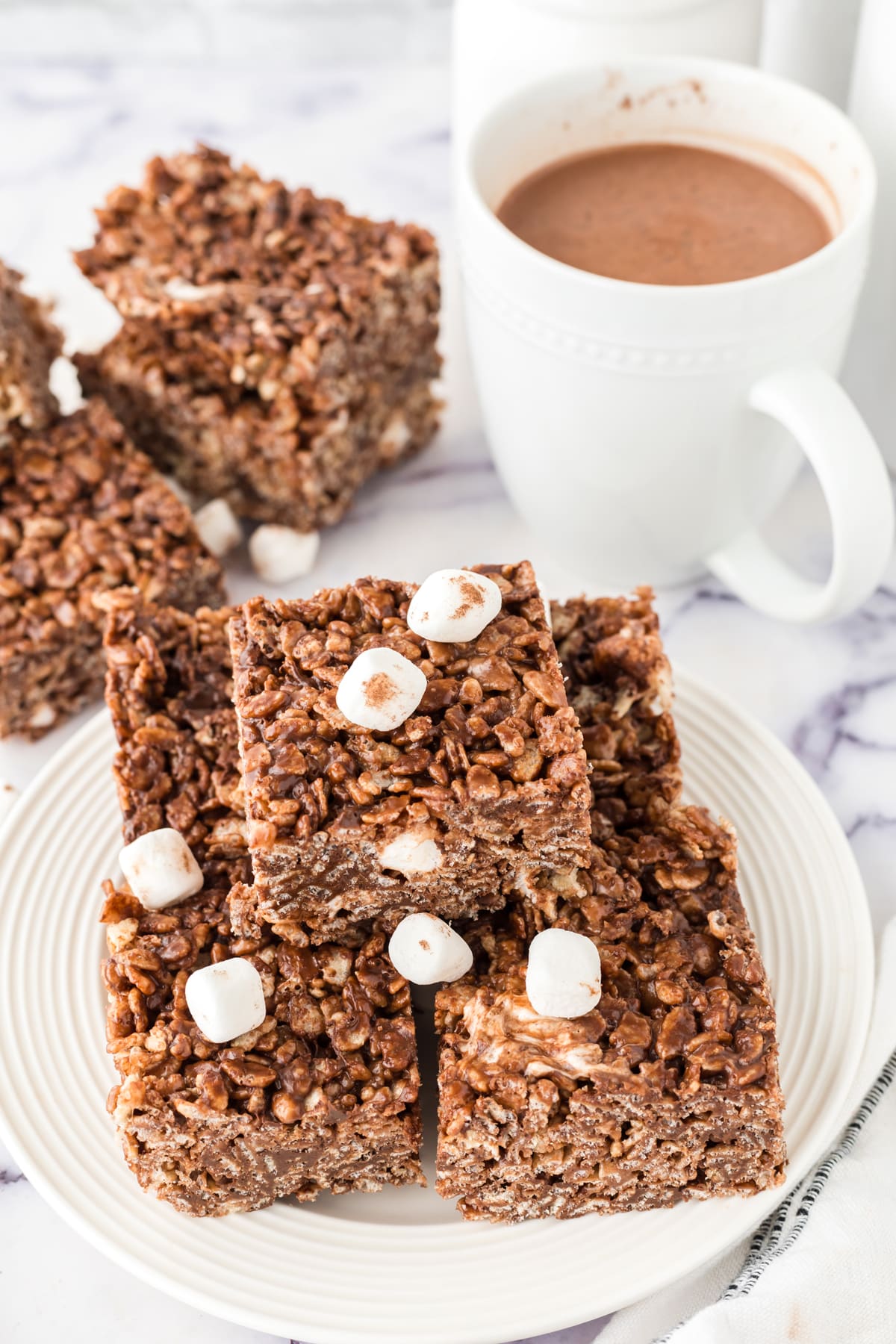 Hot Chocolate Rice Krispy Treats on a plate with a cup of hot chocolate.