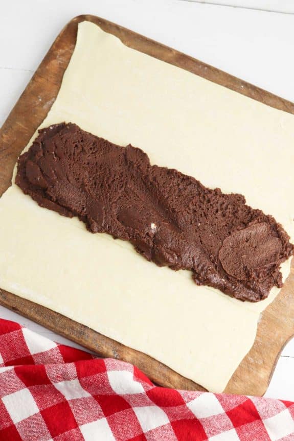 A piece of chocolate dough on a wooden cutting board.