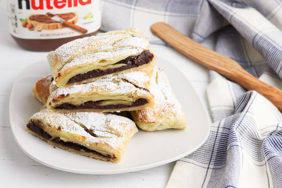 Nutella pastries on a plate next to a jar of nutella.