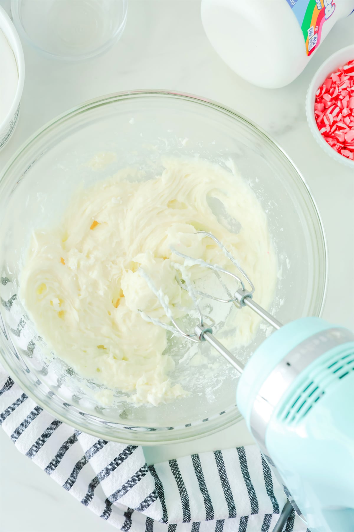 Mixing sugar and cream cheese in a bowl as one process of preparing Peppermint Fluff