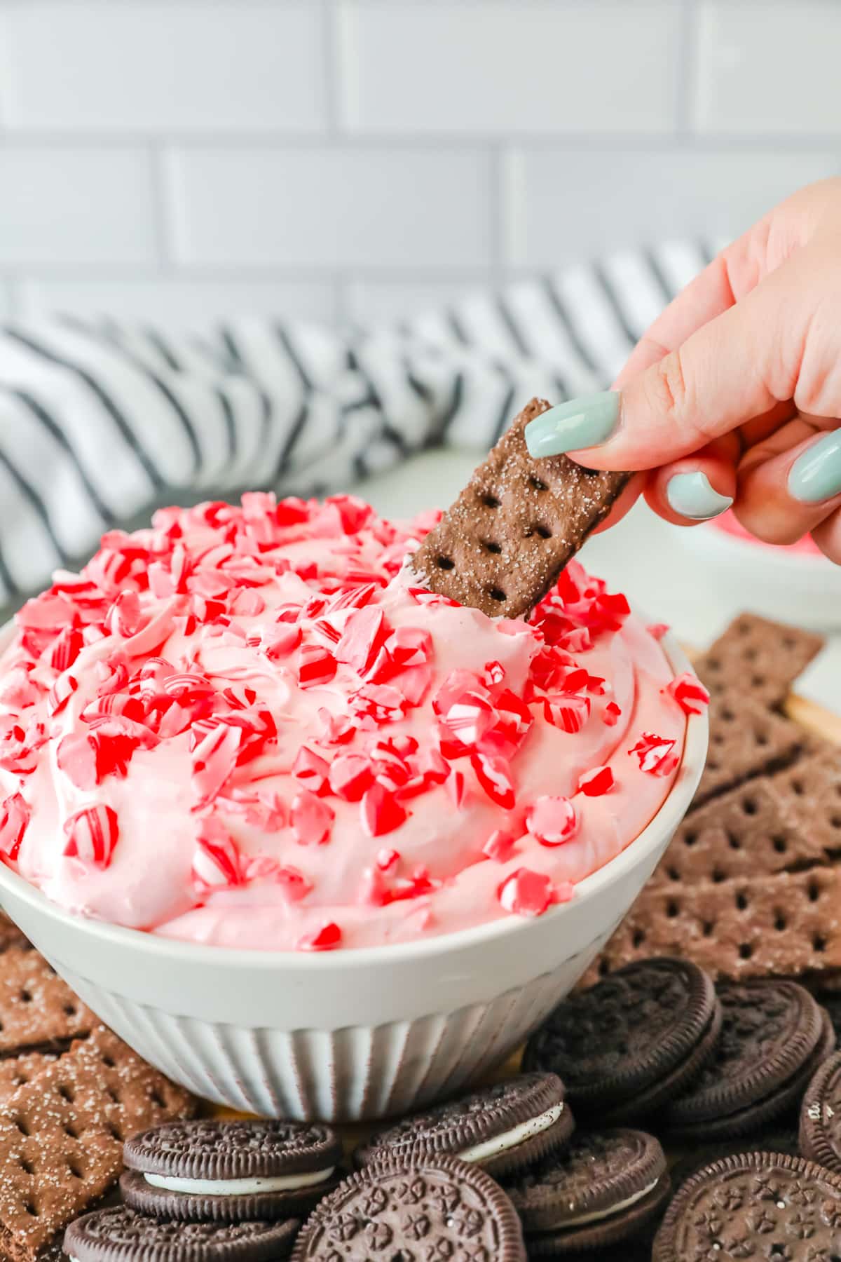 A hand is dipping a cracker into a bowl Peppermint Fluff