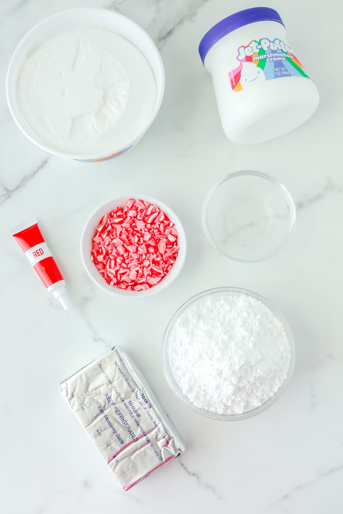 The ingredients for Peppermint Fluff are the following: cream cheese, softened, powdered sugar, marshmallow cream, frozen whipped topping, thawed, peppermint extract, red gel food coloring and crushed candy canes