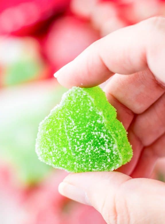 A person holding a green Christmas gumdrop candy.