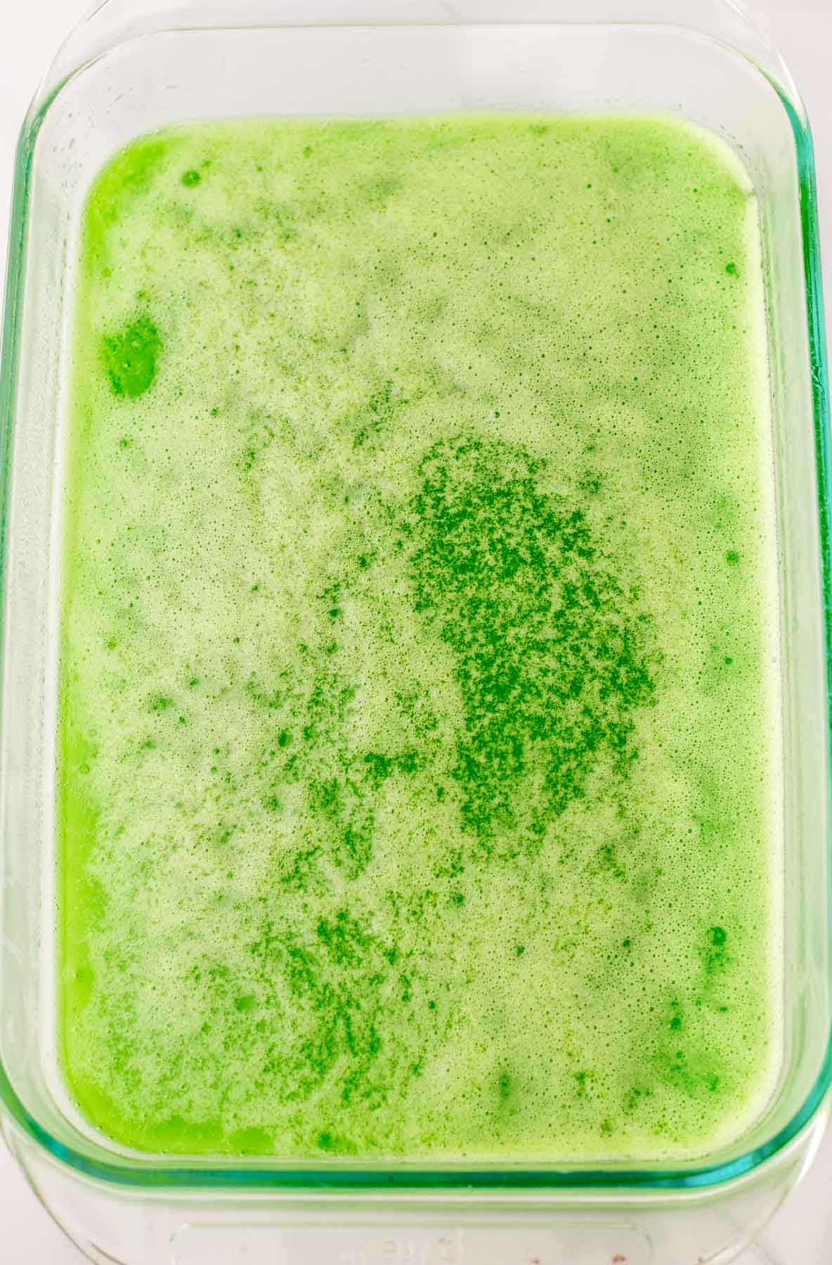 A bowl of green liquid in a glass dish.
