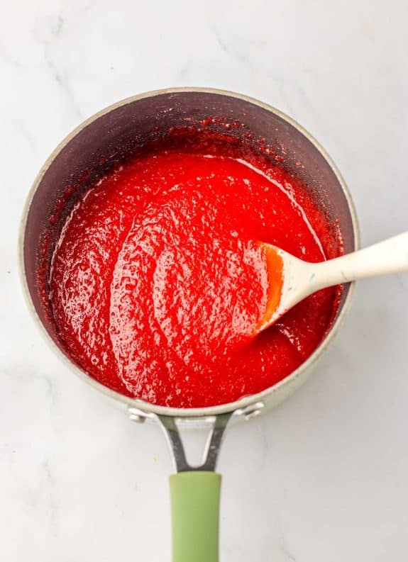 Red gelatin in a pan with a spoon.
