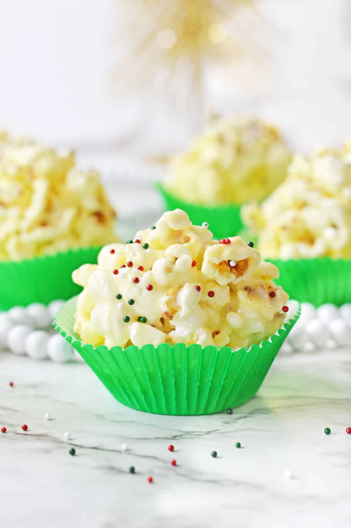 A group of Christmas popcorn balls in green cupcake liners