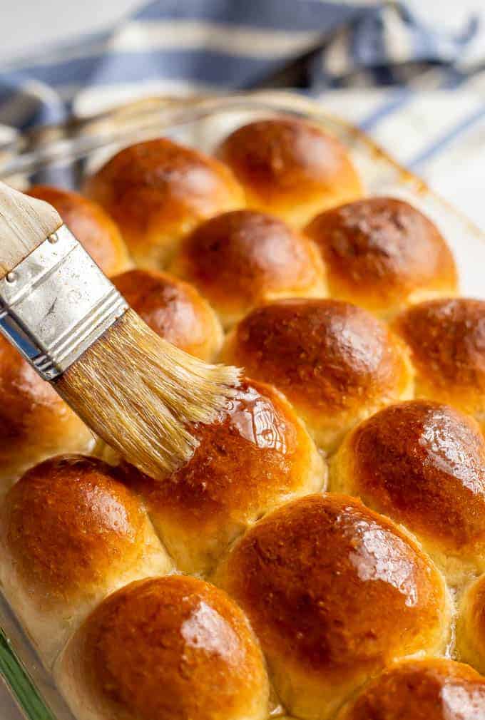 A brush is being used to brush the bread rolls with butter a perfect side dish for prime rib
