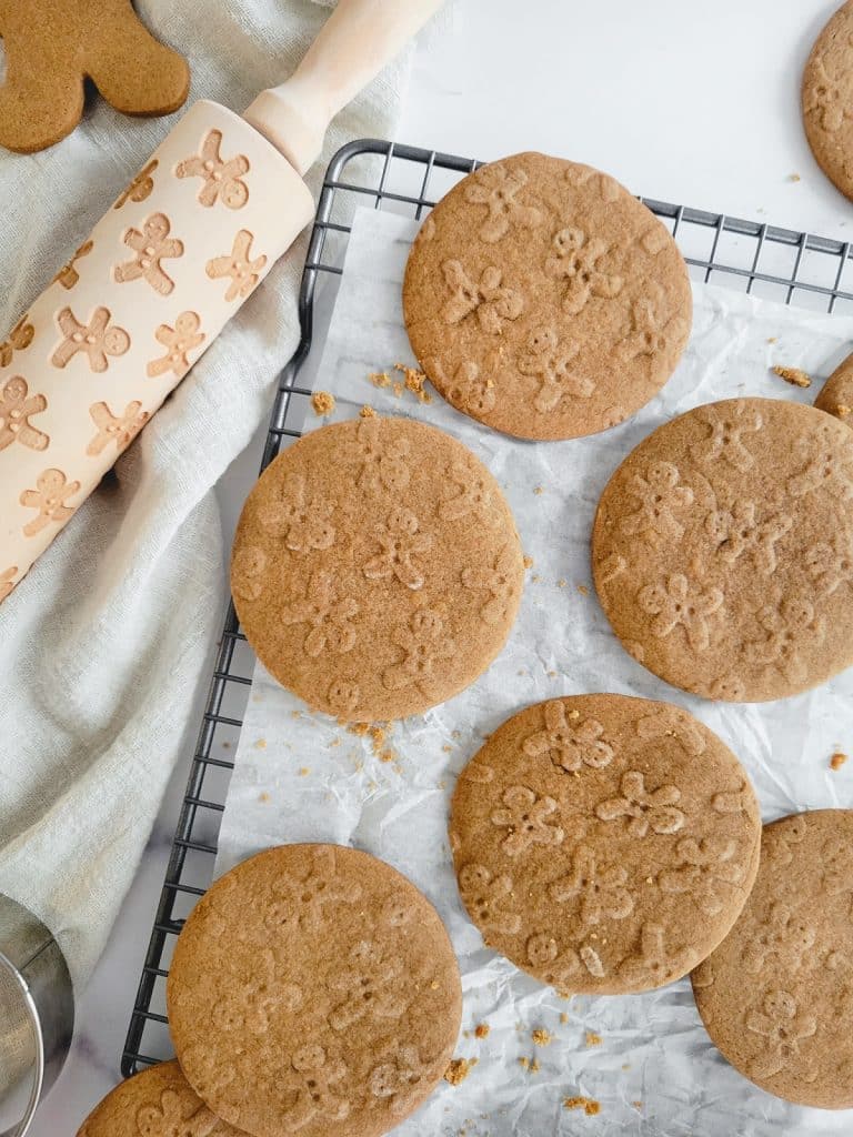 Ginger cookies on a cooling rack with a rolling pin.