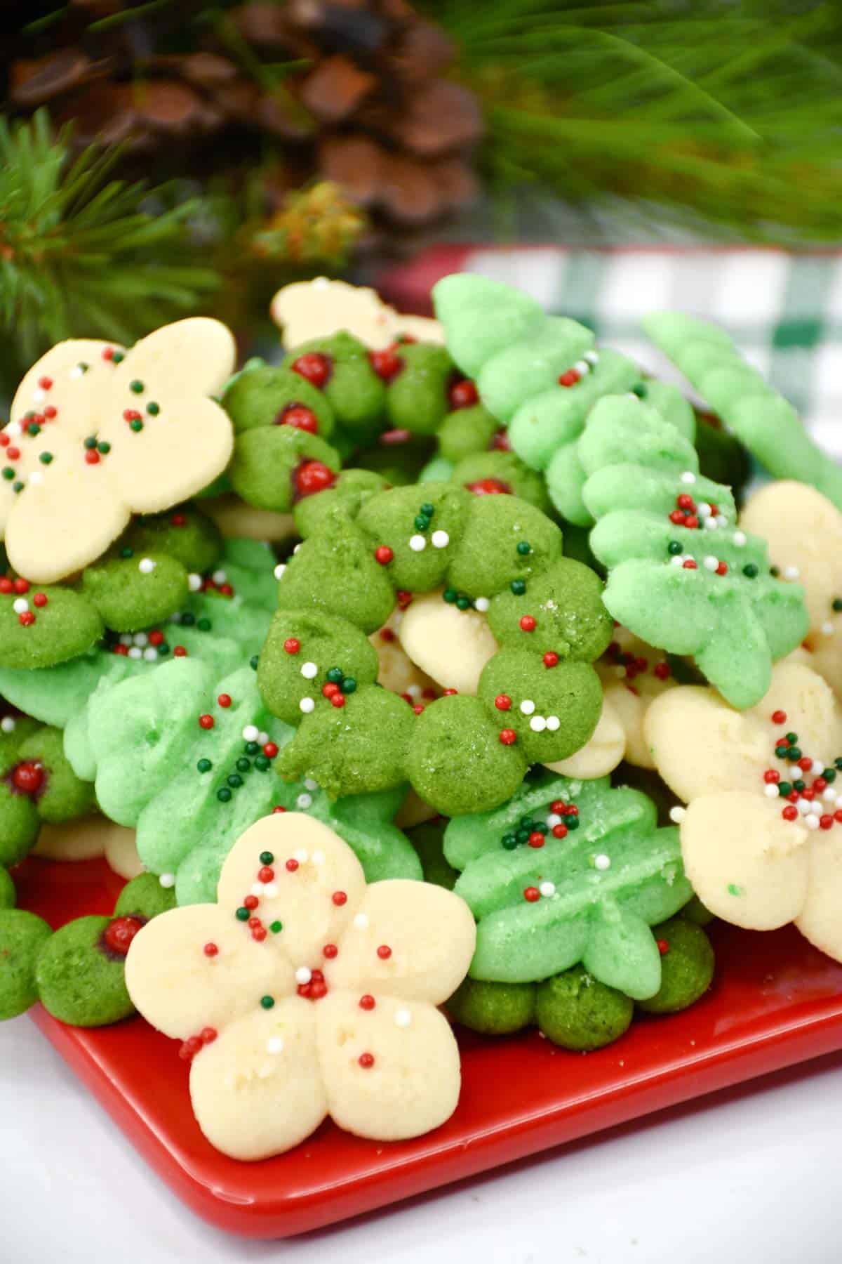 Christmas cookies on a red plate with green and white decorations.