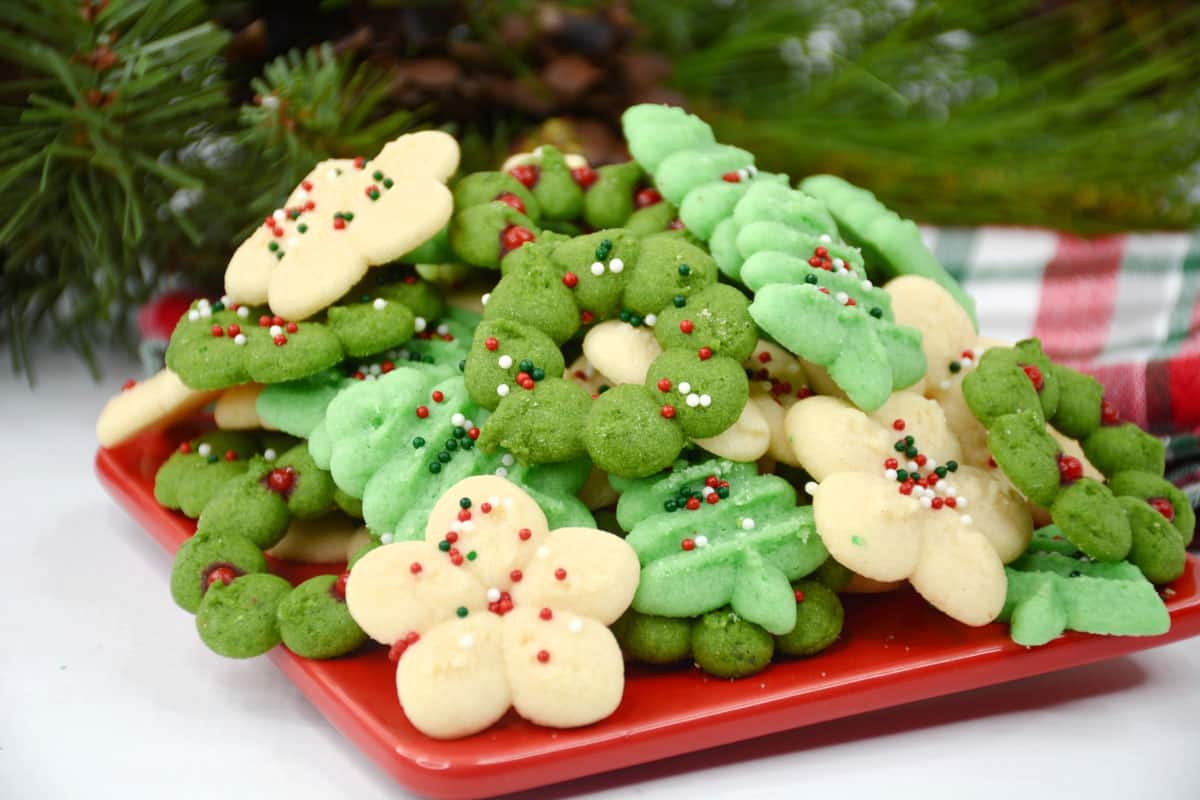 Christmas cookies on a red plate with green and white sprinkles.