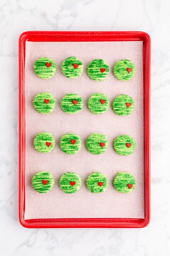 green striped Grinch red velvet Oreos on red baking tray