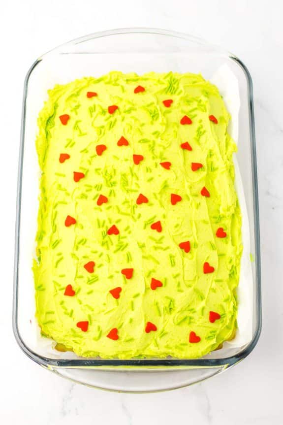 A cake with green frosting in a glass dish.