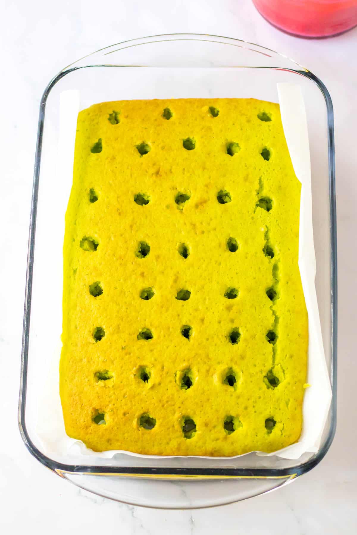 A glass baking dish with a yellow cake in it with holes in the top.