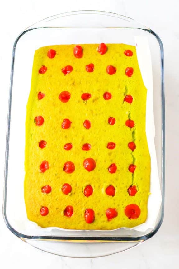 A yellow cake with red cherries on top.