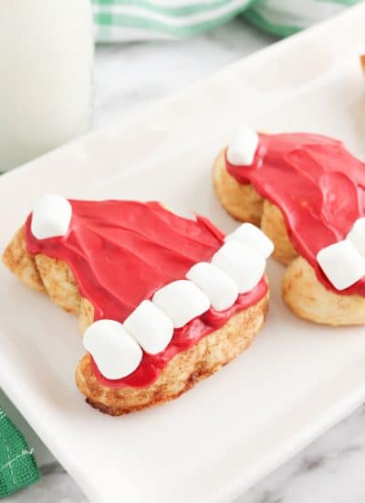 Three santa hat cookies on a plate.