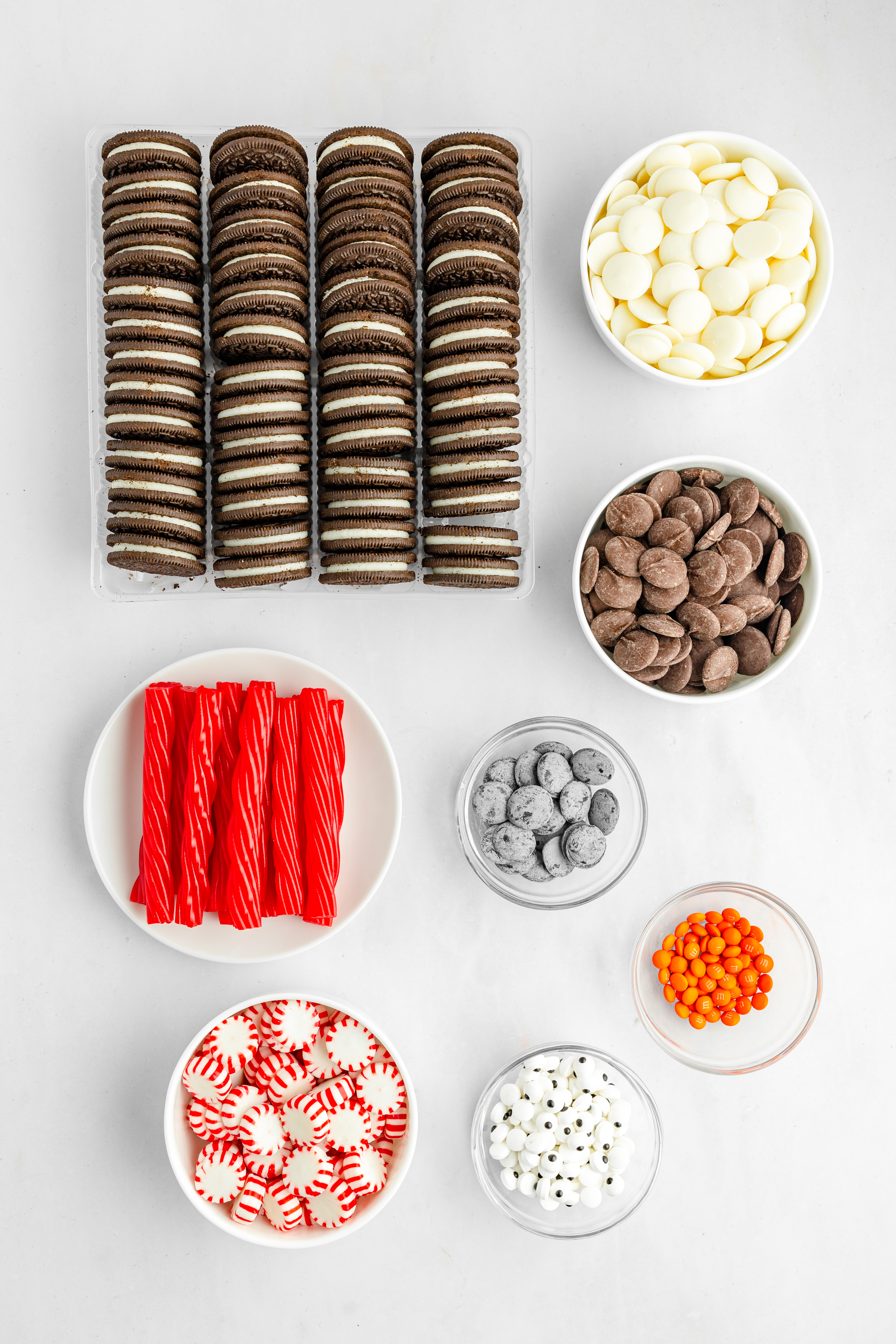 Oreos, white chocolate, chocolate candy melts, candy eyes, peppermints, and licorice on white counter
