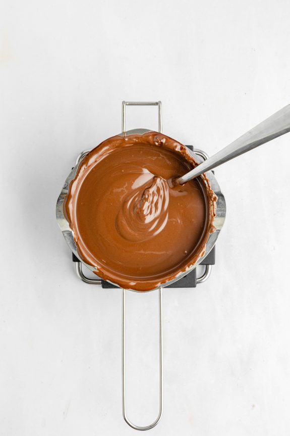 A spoon is being used to stir chocolate in a pan.