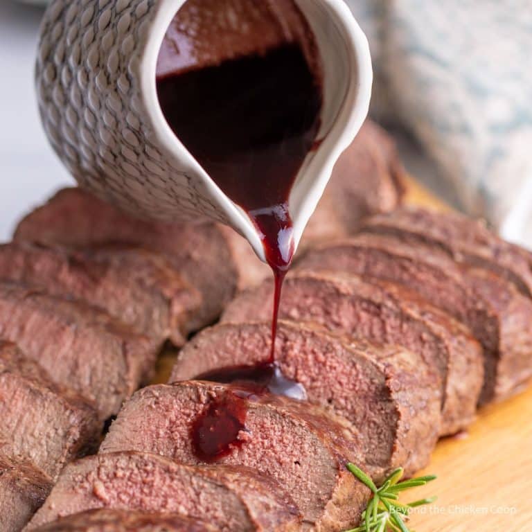 A bottle of red wine is being poured over a piece of steak.