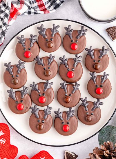 Chocolate reindeer cookies on a plate with pine cones.