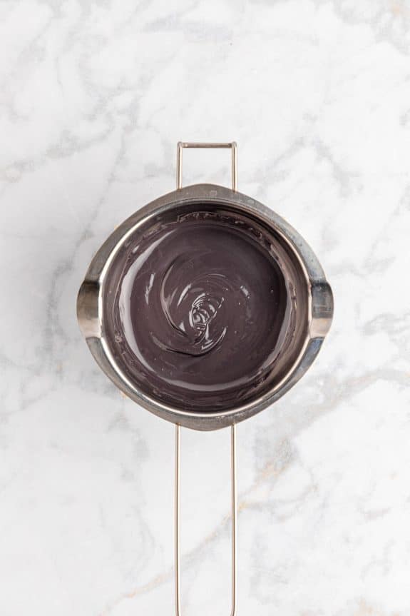 Chocolate ganache in a metal pan on a marble table.