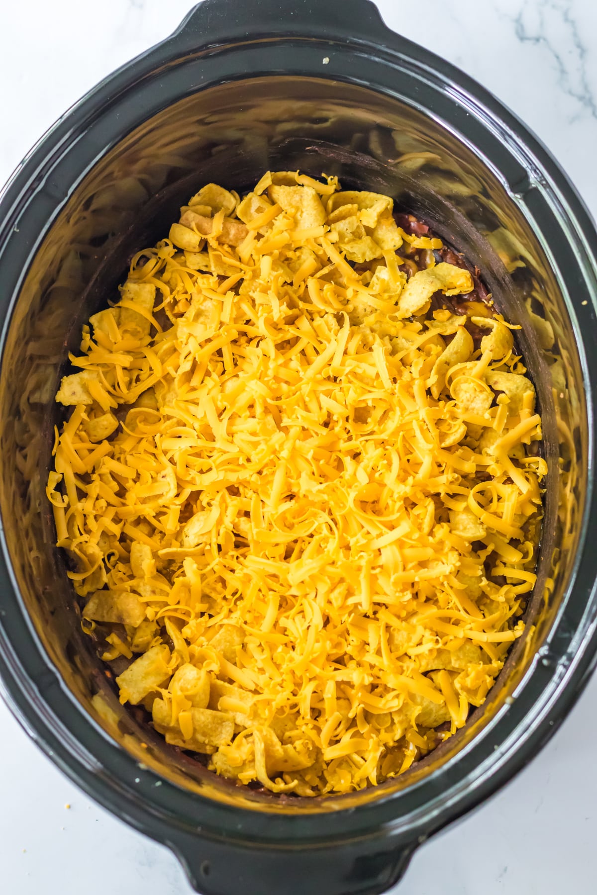 Another process in preparing Slow Cooker Frito Casserole is to add shredded cheese in a crockpot.