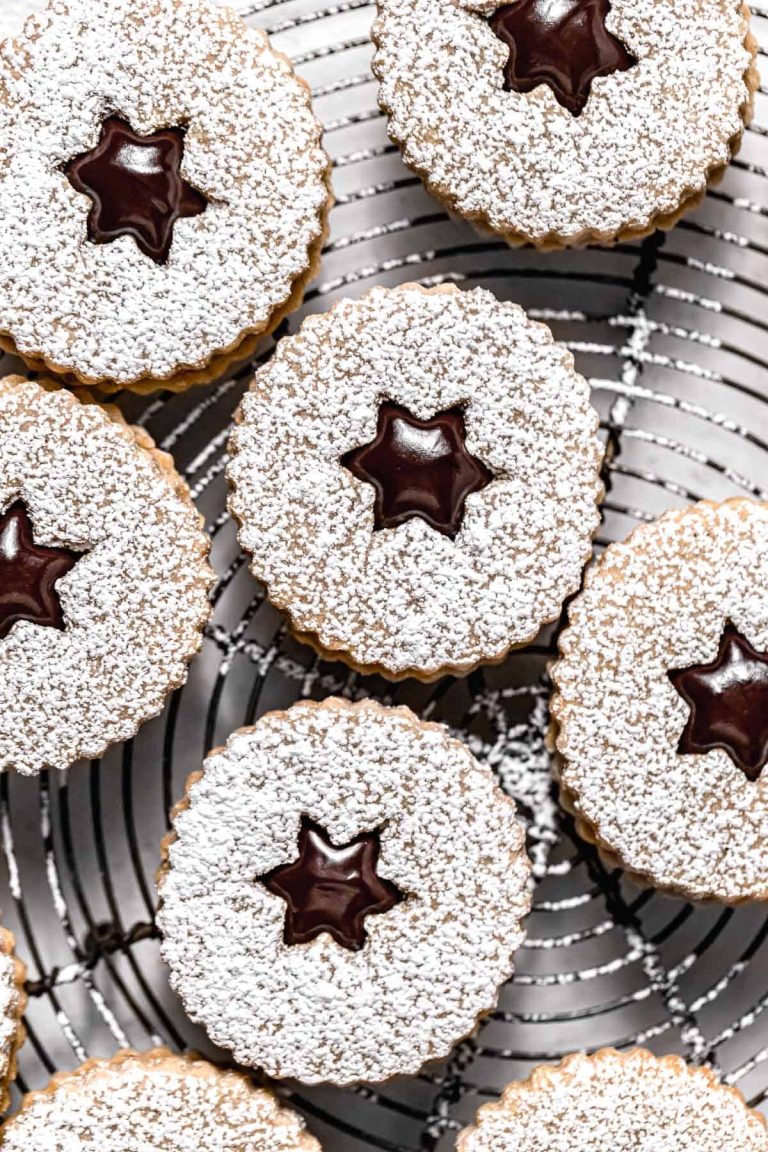 Cookies with powdered sugar and stars on a cooling rack.