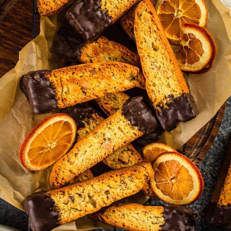A plate of biscotti with chocolate and orange slices.